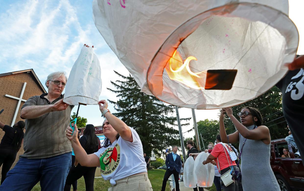 David Guran of Akron, left, and Betta Deblasio of Tallmadge, center, light a paper lantern during a Thursday memorial in Akron for Jayland Walker, a 25-year-old Black man who was shot and killed by Akron police two years ago.