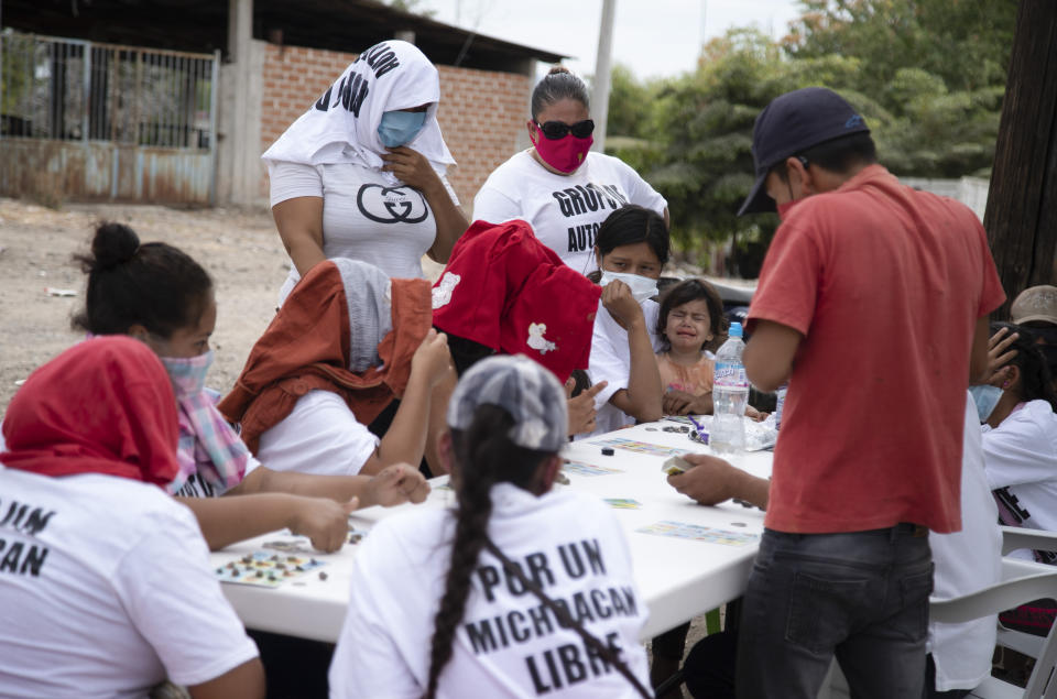 Women who say they are part of a female-led, self-defense group, some wearing T-shirts with a message that reads in Spanish: "For a free Michoacan," play board games at a check-point they set up to protect the entrance of their town of El Terrero, in Michoacan state, Mexico, Thursday, Jan. 14, 2021. Many of the women vigilantes in the hamlet of El Terrero have lost sons, brothers or fathers in the fighting. (AP Photo/Armando Solis)