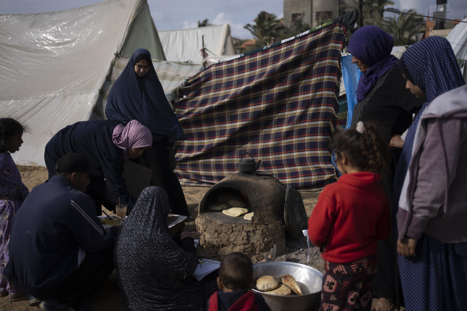 Palestinians displaced by the Israeli ground offensive on the Gaza Strip cook at the makeshift tent camp in Rafah on Tuesday, Jan. 23, 2024. (AP Photo/Fatima Shbair)