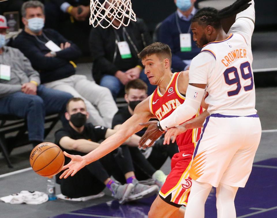 Atlanta Hawks guard Bogdan Bogdanovic (13) passes the ball while defended by Phoenix Suns forward Jae Crowder (99) during the second quarter in Phoenix on March 30, 2021.