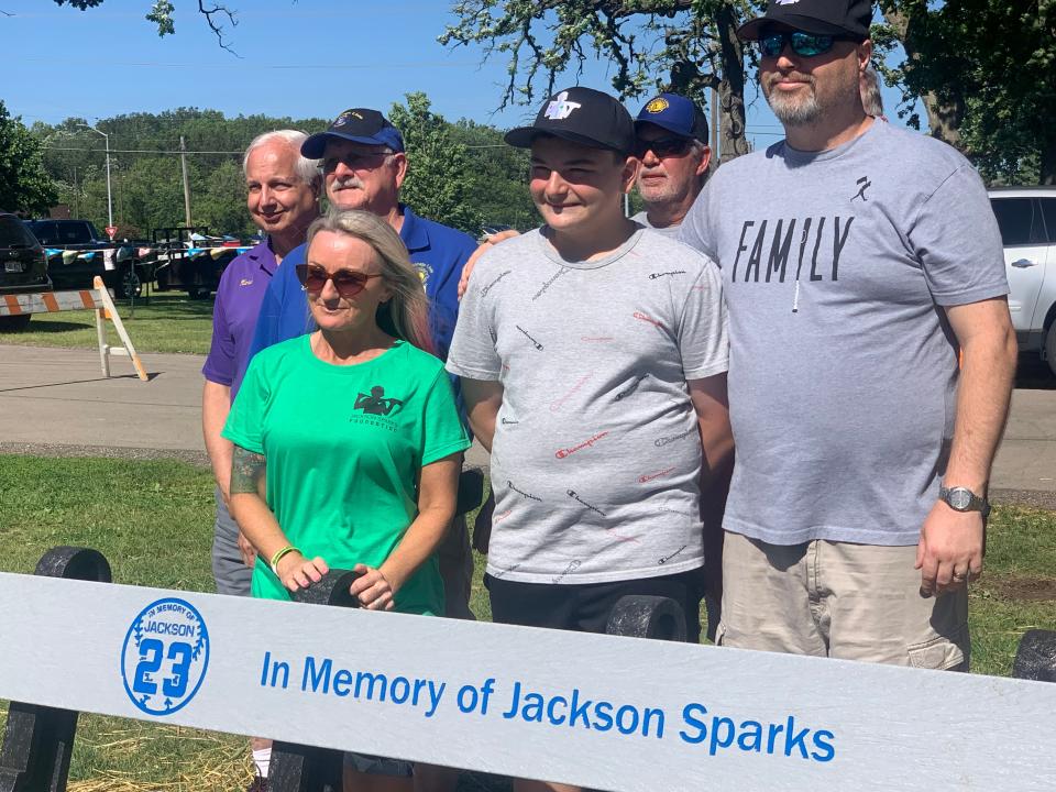 Parents Sheri and Aaron Sparks flank their son, Tucker, behind the memorial bench erected in Jackson Sparks' honor and dedicated June 16 at Field Park in the village of Mukwonago. Jackson, 8, an avid baseball player, was one six people killed by an angry driver in the Waukesha Christmas Parade in November 2021.