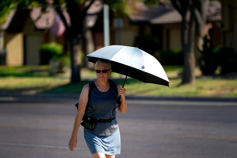 A lady uses an umbrella for shade to combat high temperatures in Phoenix.