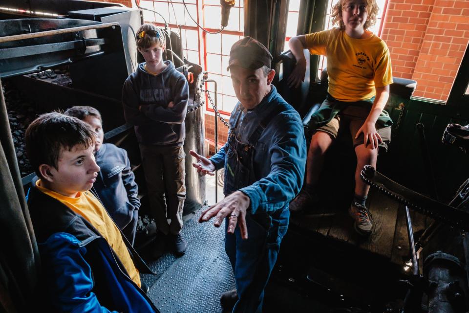 Volunteer Tim Botti teaches Scouts from Strasburg Troop 72 about the functionality of steam locomotives during the railroad merit badge program at the Age of Steam Roundhouse Museum in Sugarcreek.