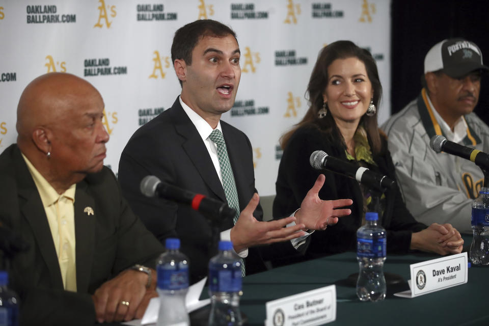 Oakland Athletics President Dave Kaval, second from left, gestures beside Oakland Mayor Libby Schaaf during a media conference Wednesday, Nov. 28, 2018, in Oakland, Calif. The Oakland Athletics have found a location for their modern new ballpark, announcing plans to build near Jack London Square along the water. At left is President of the Board of Port Commissioners Ces Butner, Oakland City Council President Larry Reid is seen at right. (AP Photo/Ben Margot)