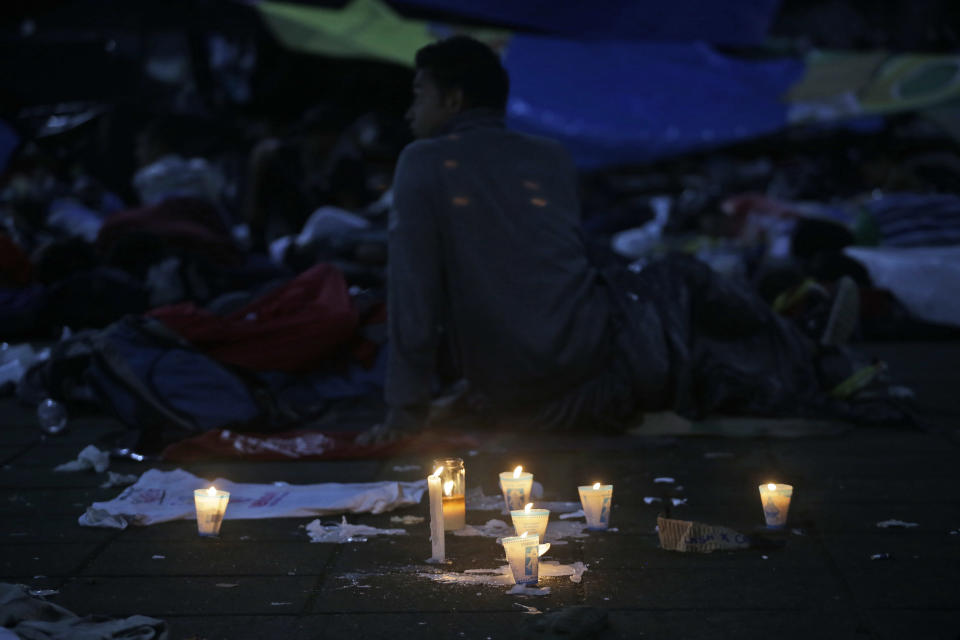 Candles arranged in the shape of a cross serve as a simple memorial for a migrant man who died the day before after he fell from the back of a moving vehicle while traveling with a caravan to the U.S., at the central park in Huixtla, Mexico, Tuesday, Oct. 23, 2018. The caravan, estimated to include more than 7,000 people, had advanced but still faced more than 1,000 miles, and likely much further, to the end of the journey. (AP Photo/Moises Castillo)