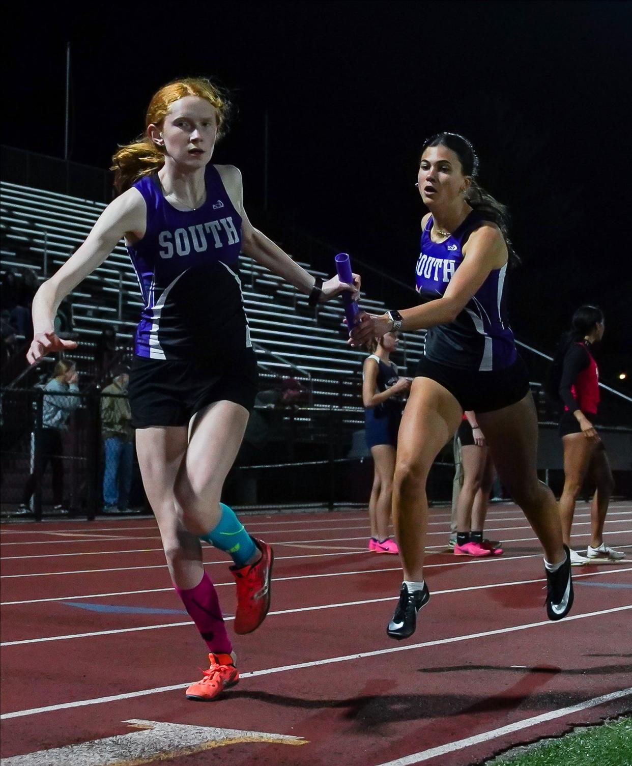 Bloomington South’s Lexi Kollbaum receives the baton from Helena Cutshall in the girls' 1,600-meter relay during the Conference Indiana track meet at Bloomington North on Friday, April 26, 2024.