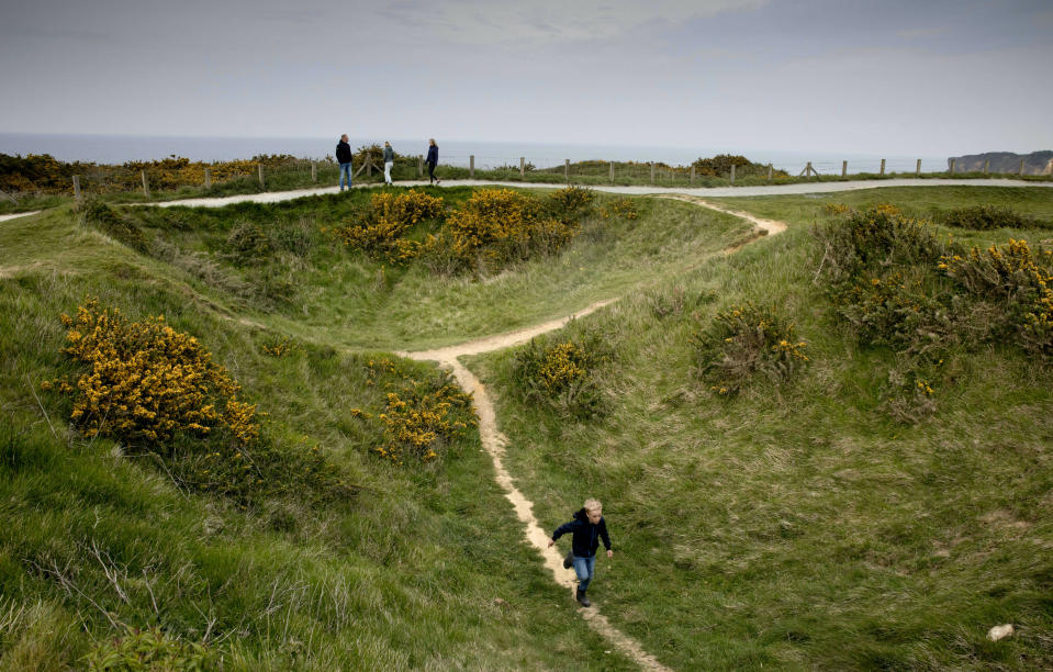 In this May 1, 2019, photo, a young boy runs down a path going through a World War II bomb crater at Pointe du Hoc, overlooking Omaha Beach, in Saint-Pierre-du-Mont, Normandy, France. On June 6, 1944, U.S. Rangers scaled the high coastal cliffs to capture a German gun battery. (AP Photo/Virginia Mayo)