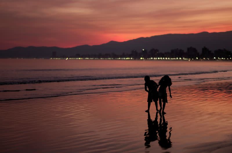 FILE PHOTO: Children walk on a beach during sunset in Praia Grande