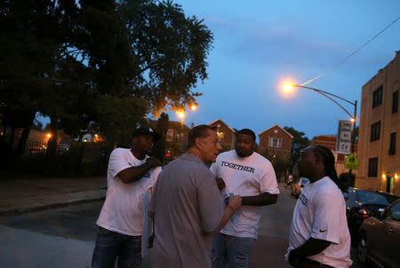 Father Michael Pfleger (2nd L) speaks with participants in a weekly night-time peace march through the streets of a South Side neighborhood in Chicago, Illinois, September 16, 2016. REUTERS/Jim Young