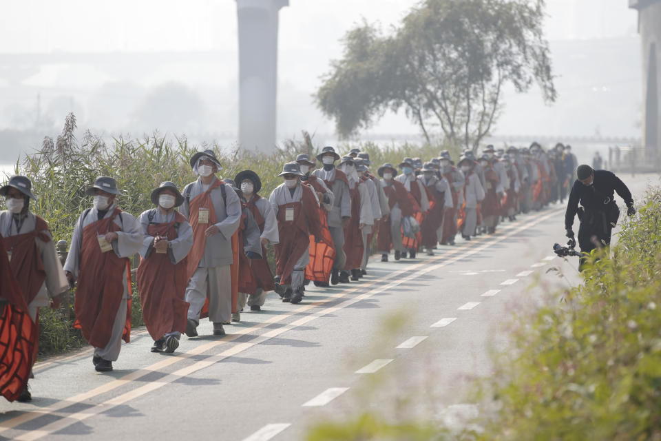 Buddhist monks and believers walk along a stream in Seoul, South Korea, Tuesday, Oct. 27, 2020. About 100 monks and followers marched the 500 kilometer (310 mile) pilgrimage to pray for the country to overcome the coronavirus. (AP Photo/Lee Jin-man)