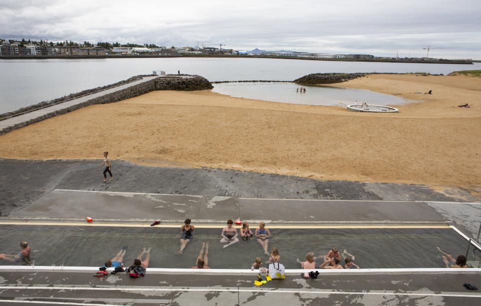 People relax in a hot tub in Nauthólsvík, a small neighbourhood in Reykjavik, Iceland Saturday Aug. 1, 2020. In Iceland, a nation so safe that its president runs errands on a bicycle, U.S. Ambassador Jeffery Ross Gunter has left locals aghast with his request to hire armed bodyguards. He's also enraged lawmakers by casually and groundlessly hitching Iceland to President Donald Trump's controversial "China virus” label for the coronavirus. (AP Photo/Árni Torfason)