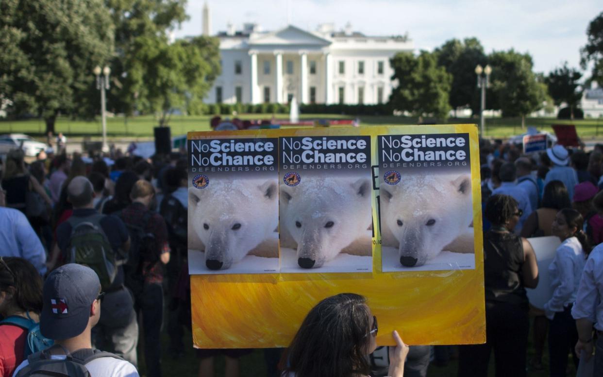 A protester holds up a sign during a rally against the United States backing out of the Paris Climate accord - AFP