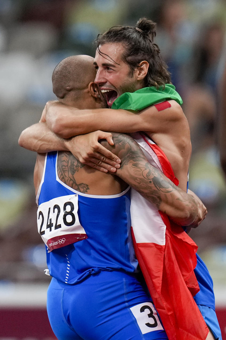 Lamont Jacobs, left, of Italy, celebrates after winning the men's the 100-meter final with high jump winner Gianmarco Tamberi, also of Italy, at the 2020 Summer Olympics, Sunday, Aug. 1, 2021, in Tokyo. (AP Photo/Petr David Josek)