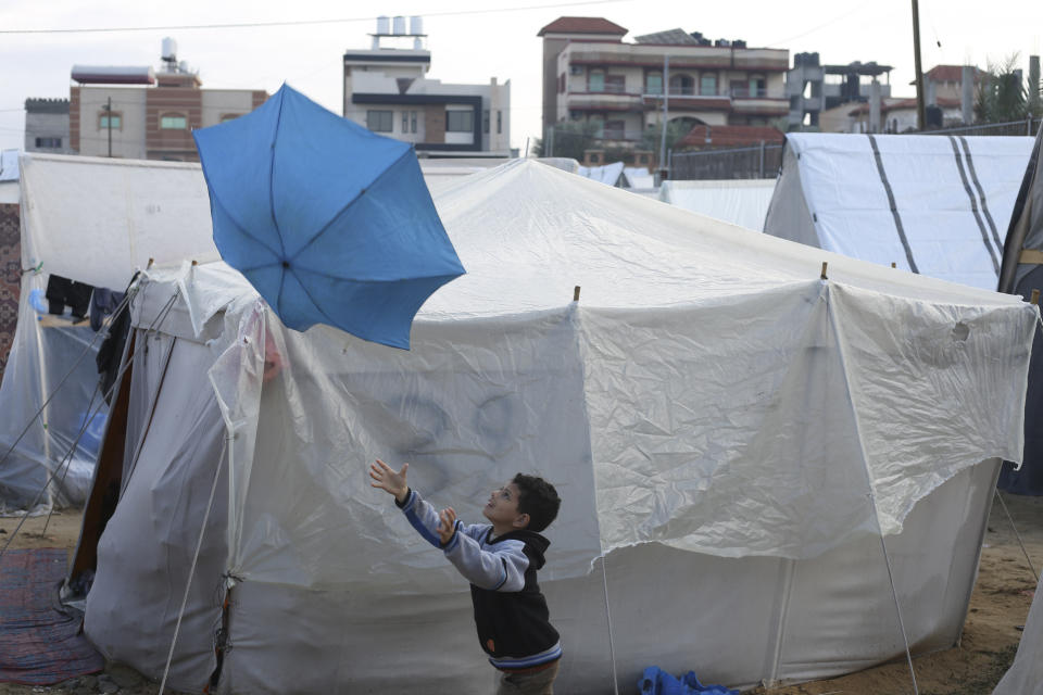 A Palestinian boy displaced by the Israeli bombardment plays with an umbrella outside a makeshift tent in Rafah, Gaza Strip, Tuesday, Jan. 2, 2023. (AP Photo/Hatem Ali)