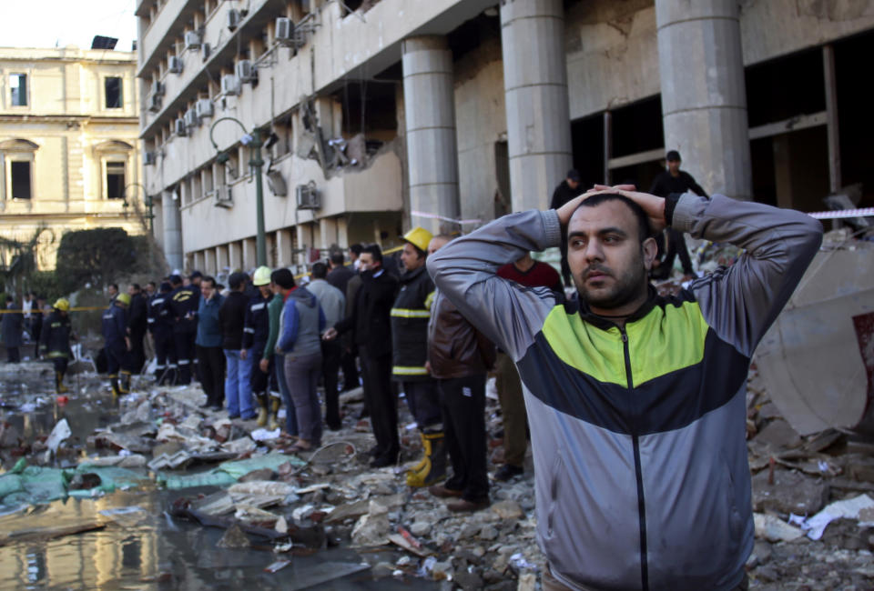 FILE - I this file photo taken Friday, Jan. 24, 2014, an Egyptian man stands in the rubble after an explosion at the Egyptian police headquarters in downtown Cairo. The militant group Ansar Beit al-Maqdis, which has waged a campaign of bombings and assassinations for months in Egypt, has quickly advanced in weaponry and sophistication of attacks, drawing on the experience of Egyptians who fought in Syria. (AP Photo/Khalil Hamra, File)