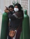 A woman pulls her empty oxygen tank to the line of people waiting outside a shop that refills them in the Villa El Salvador shantytown of Lima, Peru, Thursday, Jan. 21, 2021, amid the COVID-19 pandemic. The store is limited to refilling 20 tanks a day. (AP Photo/Martin Mejia)