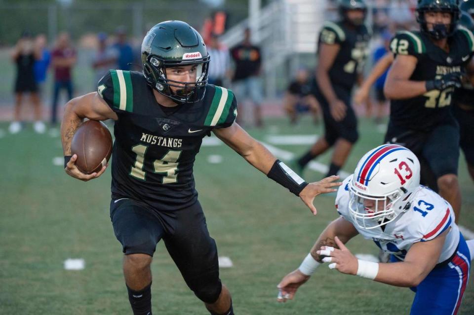 Monterey Trail Mustangs quarterback Joseph Barrientos (14) runs the ball around the Folsom Bulldogs’ Mason Kelly (13) in the first half of the opening night game on Aug. 18 at Monterey Trail High School in Elk Grove.