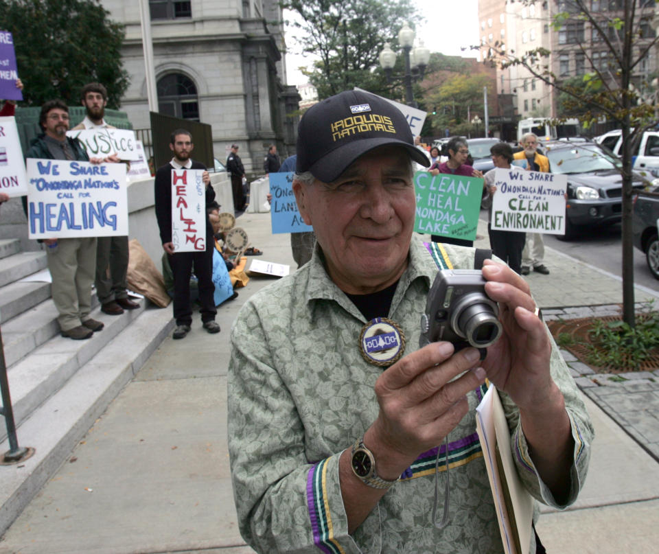 FILE - This Oct. 11, 2007 file photo shows Oren Lyons of the Onondaga Council of Chiefs taking photos outside the federal courthouse in Albany, N.Y., after arguments were heard in the Onondaga Indian Nation's land claim case against New York state. A Native American nation is asking the international community to charge the United States with human rights violations in hopes of getting help with a land claim. The Onondaga Indian Nation says it plans to file a petition at the Organization of American States on Tuesday, seeking human rights violations against the United States government. They want the Inter-American Commission on Human Rights to declare that the U.S. government’s decision not to hear their lawsuit asking for the return of 2.5 million acres in upstate New York to be violations of international human rights agreements. (AP Photo/Mike Groll, File)