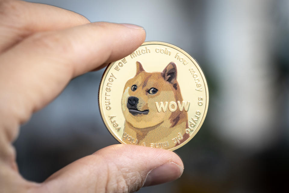 Dogecoin cryptocurrency physical coin held between two fingers. (Source: Getty)