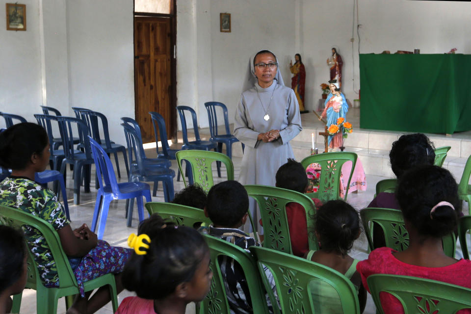 In this Oct. 23, 2018, photo, Sister Laurentina leads a prayer in a church in Fatukoko village of West Timor, Indonesia. Laurentina is one of the few people in West Timor trying to track migrant workers who have gone missing. Since 2012, she has traveled to villages across the island to run educational meetings about the dangers of traffickers. (AP Photo/Tatan Syuflana)