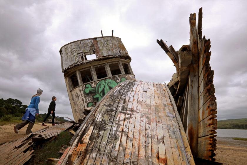 INVERNESS, CA - APRIL 23, 2024 - Diane Oppenheimer, right, from Detroit, and her friend Charity Kahn, 54, from Oakland, check out the Inverness Shipwreck in Inverness, California, on April 23, 2024. Time is apparently running out for California's "Inverness Shipwreck," an old wooden boat that became an Instagram star as it rotted on a shoreline north of San Francisco in Inverness, California on April 23, 2024. Recent storms have made a shambles of the forlorn vessel named Point Reyes, which was already deteriorated from the over-attention of visitors to the Marin County coast, San Francisco Bay news media reported this week. "The National Park Service is aware that additional damage occurred to the vessel as a result of the most recent storms and tides," Point Reyes National Seashore officials said in a statement to the SFGATE news site. The boat was built in the 1940s and was used for transportation and fishing before it was abandoned years ago, aground near the community of Inverness on a section of the Tomales Bay shoreline that is part of the Point Reyes National Seashore. (Genaro Molina/Los Angeles Times)