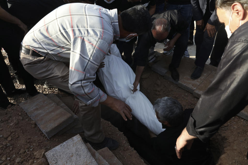 Relatives bury body of their loved one, a Covid-19 victim, at Behesht-e-Masoumeh cemetery just outside the city of Qom, some 80 miles (125 kilometers) south of the capital Tehran, Iran, Wednesday, Sept. 15, 2021. (AP Photo/Vahid Salemi)