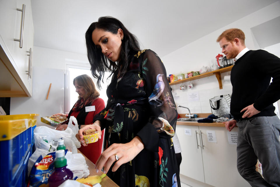 Meghan and Prince Harry in the One25 kitchen with a volunteer. (Photo: TOBY MELVILLE via Getty Images)
