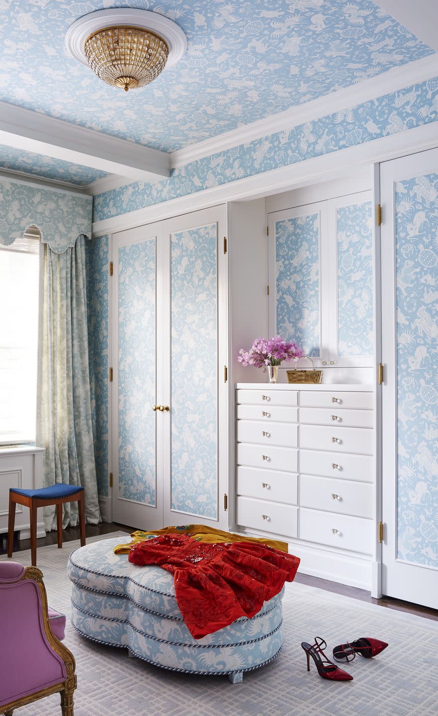 a dressing room with closet doors and built in drawers covered in a light blue and white wallpaper or fabric