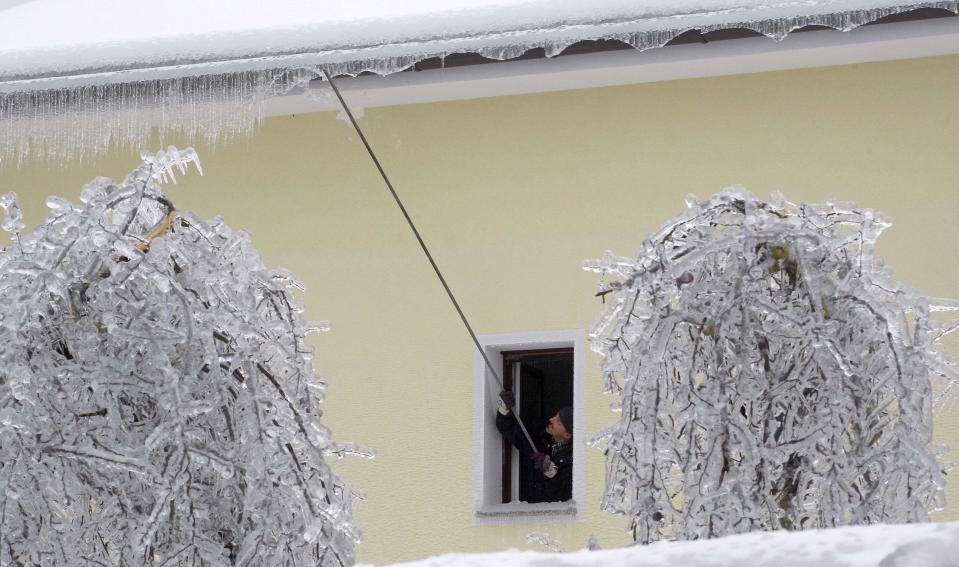 Un hombre remueve los témpanos que se formaron en su techo, en Prestranek. REUTERS/Srdjan Zivulovic.