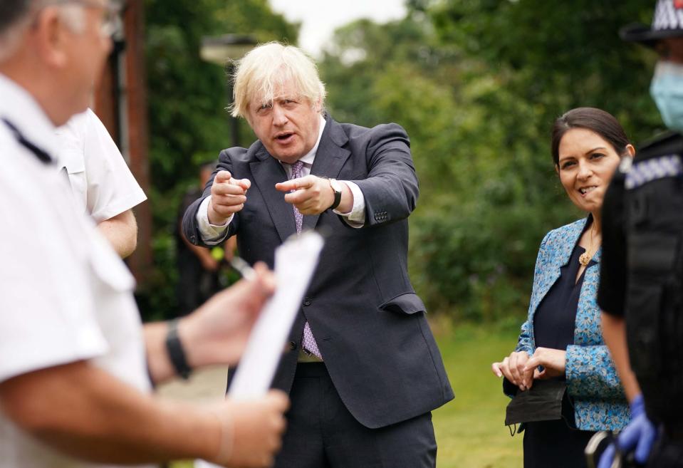 Britain's Prime Minister Boris Johnson (C) and Britain's Home Secretary Priti Patel (R) visit Surrey Police headquarters in Guildford, south west of London, on July 27, 2021 to coincide with the publication of the government's plans to tackle crime. (Photo by Yui Mok / POOL / AFP) (Photo by YUI MOK/POOL/AFP via Getty Images)