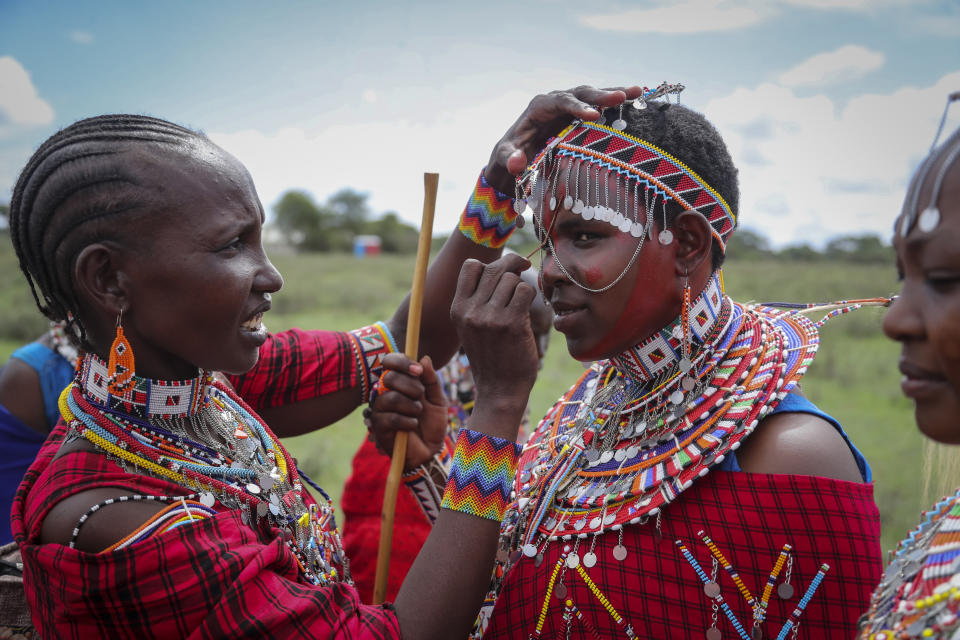 A Maasai woman paints the face of another as they prepare to watch the Maasai Olympics in Kimana Sanctuary, southern Kenya Saturday, Dec. 10, 2022. The sports event, first held in 2012, consists of six track-and-field events based on traditional warrior skills and was created as an alternative to lion-killing as a rite of passage. (AP Photo/Brian Inganga)