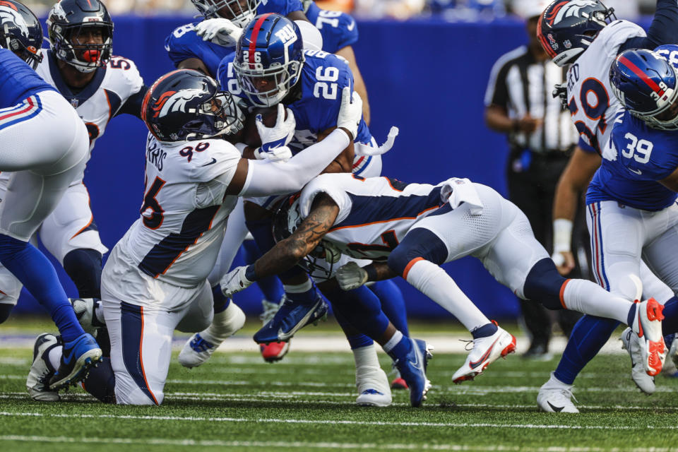 New York Giants running back Saquon Barkley (26) is tackled by Denver Broncos' Shelby Harris (96) and Kareem Jackson (22) during the first half of an NFL football game Sunday, Sept. 12, 2021, in East Rutherford, N.J. (AP Photo/Adam Hunger)