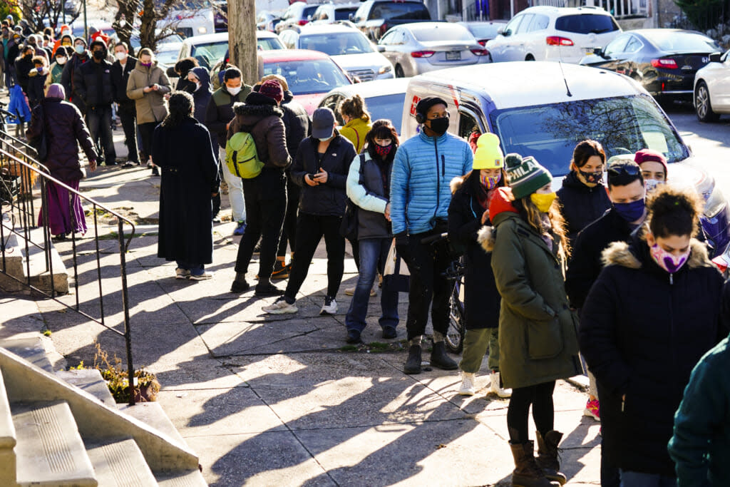 Residents wait in a line extending around the block to receive free at-home rapid COVID-19 test kits on Dec. 20, 2021 in Philadelphia. (AP Photo/Matt Rourke)