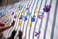 Demonstrators print their handprints on a banner after a marching against violence on the first anniversary of President Andres Manuel Lopez Obrador taking office, in Mexico City