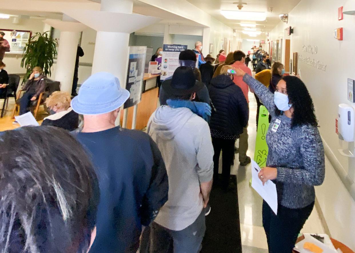 In this photo provided by The Mendocino Voice, a health care worker directs people lined up in the Adventist Health Ukiah Valley Medical Center on Monday, Jan. 4, 2021, in Ukiah, Calif. to get the Moderna COVID-19 vaccination during an emergency vaccine drive. A power failure for the freezer holding the county's ration of the Moderna vaccines forced the emergency distribution of 850 doses of that vaccine.