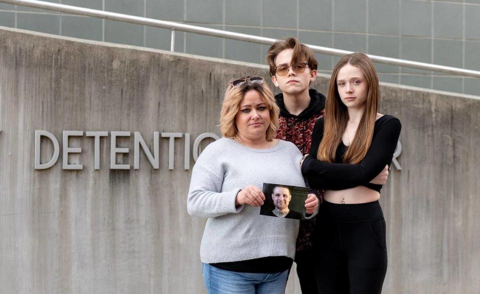 Shawna Almendarez holds a photo of her ex-husband, Ryan Everson, while posing for a photo with their children, Rielly and Nautia Everson outside the Clay County Detention Center in Liberty on Feb. 22.