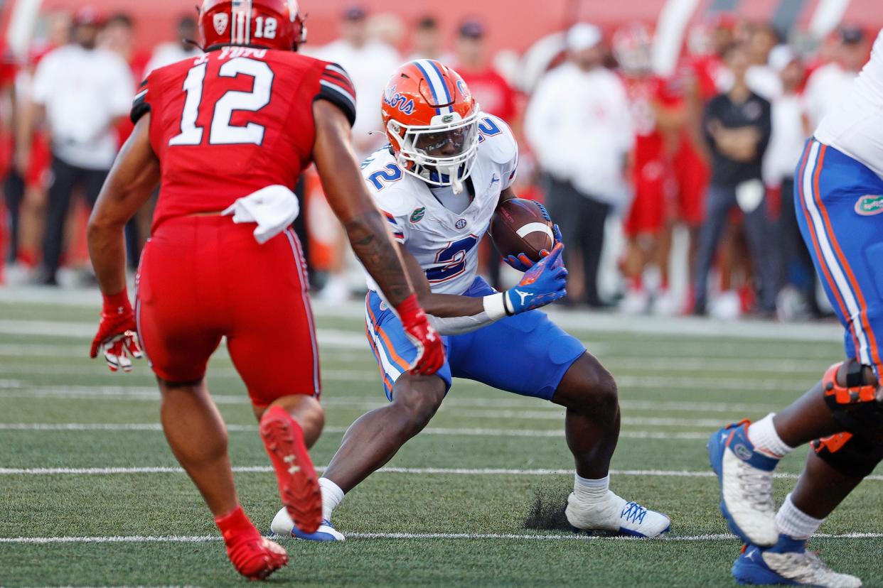 Aug 31, 2023; Salt Lake City, Utah, USA; Florida Gators running back Montrell Johnson Jr. (2) runs the bal against Utah Utes linebacker Sione Fotu (12) in the first half at Rice-Eccles Stadium. Mandatory Credit: Jeff Swinger-USA TODAY Sports