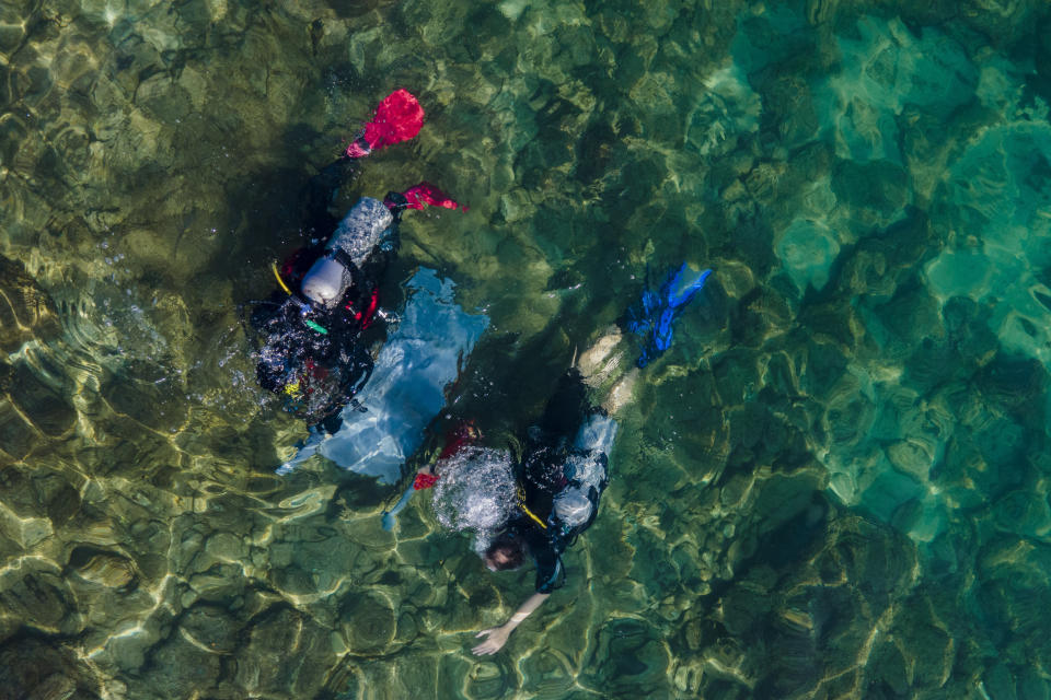 Scuba-diving volunteers collect trash during World Ocean Day event in the Mediterranean ancient Caesarea's Roman-period port, Israel, Friday, June 10, 2022. Divers visiting the ancient seaport of Caesarea on Israel's Mediterranean coast occasionally find treasure, but on Friday they searched for trash. Twenty six scuba-diving volunteers removed around 100 pounds (45 kilograms) of garbage from between the sunken pillars and submerged ruins of the historic site as part of a United Nations World Oceans Day initiative. (AP Photo/Ariel Schalit)