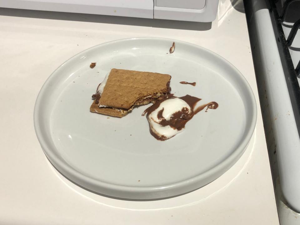 smore with a bite taken out of it and lost of marshmallow oozing out on a white plate