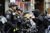 A man talks with police lining a street occupied hours earlier by protesters Wednesday, July 1, 2020, in Seattle, where streets had been blocked off in an area demonstrators had occupied for weeks. Seattle police showed up in force earlier in the day at the "occupied" protest zone, tore down demonstrators' tents and used bicycles to herd the protesters after the mayor ordered the area cleared following two fatal shootings in less than two weeks. The "Capitol Hill Occupied Protest" zone was set up near downtown following the death of George Floyd while in police custody in Minneapolis. (AP Photo/Elaine Thompson)