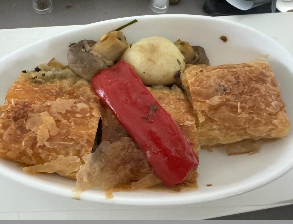 A plate with flaky pastries and roasted vegetables.