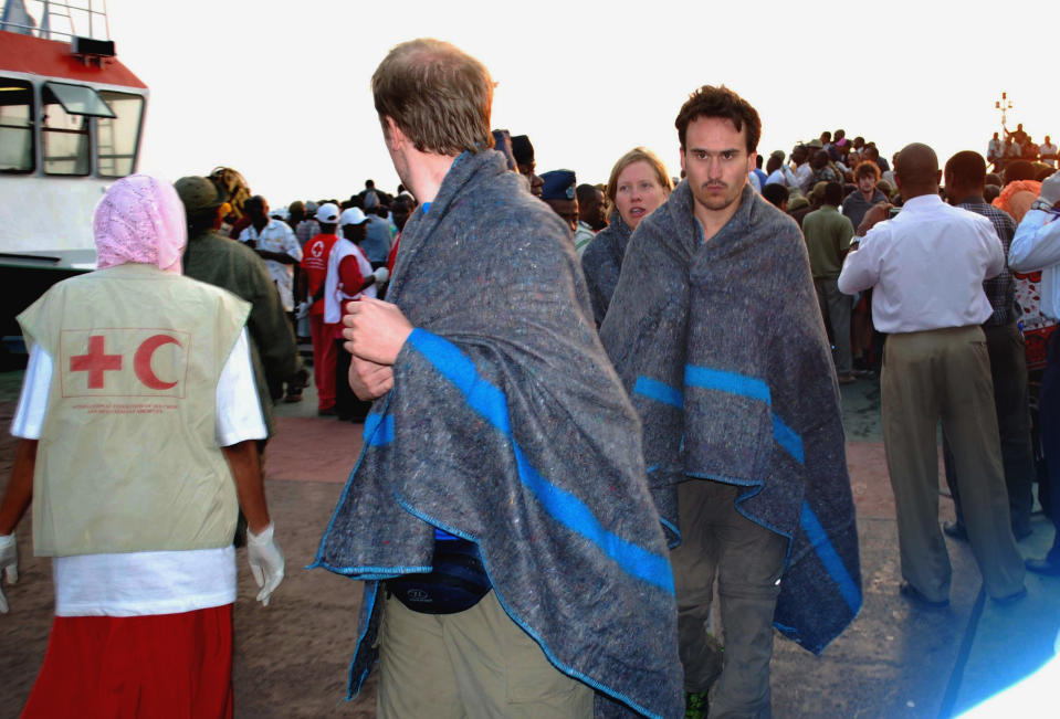 Tourists are brought ashore wrapped in blankets Wednesday, July 18, 2012 on Zanzibar island, Tanzania after ferry accident off the coast of Tanzania's island region of Zanzibar. A Zanzibar official says at least a dozen people were killed in a ferry accident off the coast of Tanzania's island region of Zanzibar. Mwinyihaji Makame, a deputy minister in the office of the president, said Wednesday it remained unclear how many passengers were on board, but witnesses said the ferry carried more than 200 people when it sank. The ferry sailed from the Tanzanian port city of Dar es Salaam and was headed for Zanzibar, which is popular with tourists.(AP Photo/ Khalfan Said)