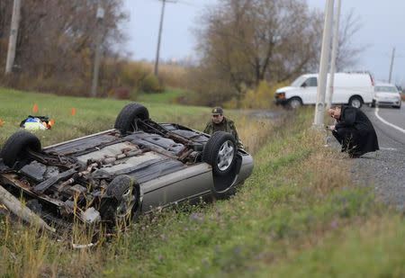 A Surete du Quebec (SQ) officer investigates an overturned vehicle in Saint-Jean-sur-Richelieu, Quebec October 20, 2014. REUTERS/Christinne Muschi