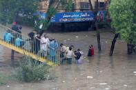 People gather and wait on stairs of a pedestrian bridge at a flooded street during the monsoon rain, as the outbreak of the coronavirus disease (COVID-19) continues, in Karachi