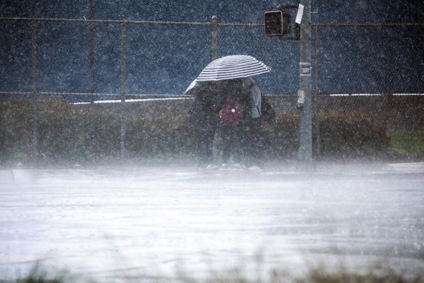 LOS ANGELES, CA - MARCH 21: Students leaving school in Van Nuys huddle under umbrellas during a passing downpour on Tuesday, March 21, 2023. (Myung J. Chun / Los Angeles Times)