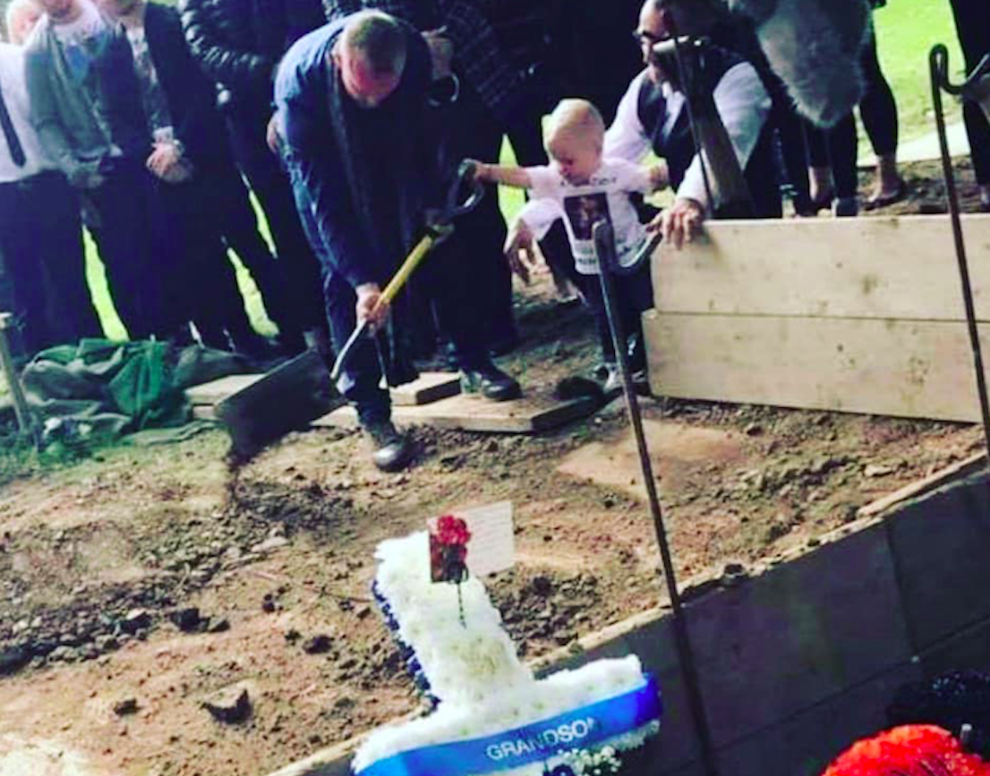 Toddler Carter Bagshaw pours soil over the grave of his father, Lewis Bagshaw (Picture: Jordan Kissack/Facebook)