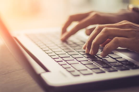 A person typing on a laptop keyboard.