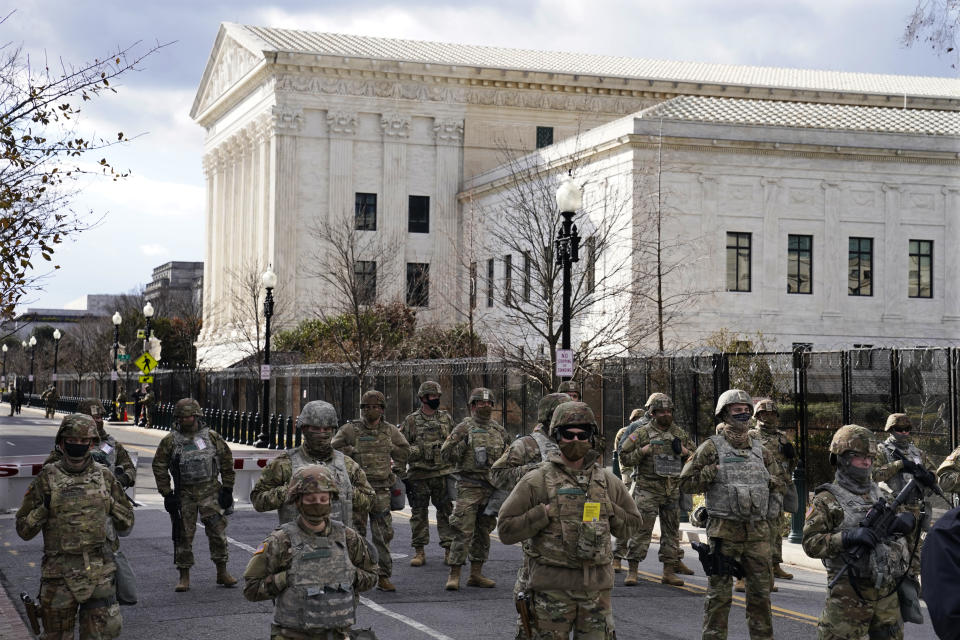 FILE - In this Wednesday, Jan. 20, 2021 file photo, members of the National Guard stand at a road block near the Supreme Court ahead of President-elect Joe Biden's inauguration ceremony in Washington. On Friday, Jan. 29, 2021, The Associated Press reported on stories circulating online incorrectly asserting Donald Trump invited National Guard members to stay at Trump Hotel in Washington so they don’t have to sleep in a cold parking garage. A spokesperson with the National Guard Bureau told The Associated Press they had not received any offers to stay at Trump International Hotel Washington, D.C., the former president’s hotel. (AP Photo/John Minchillo)
