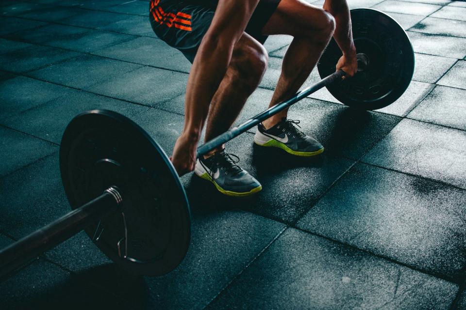 Person crouching, about to lift a barbell