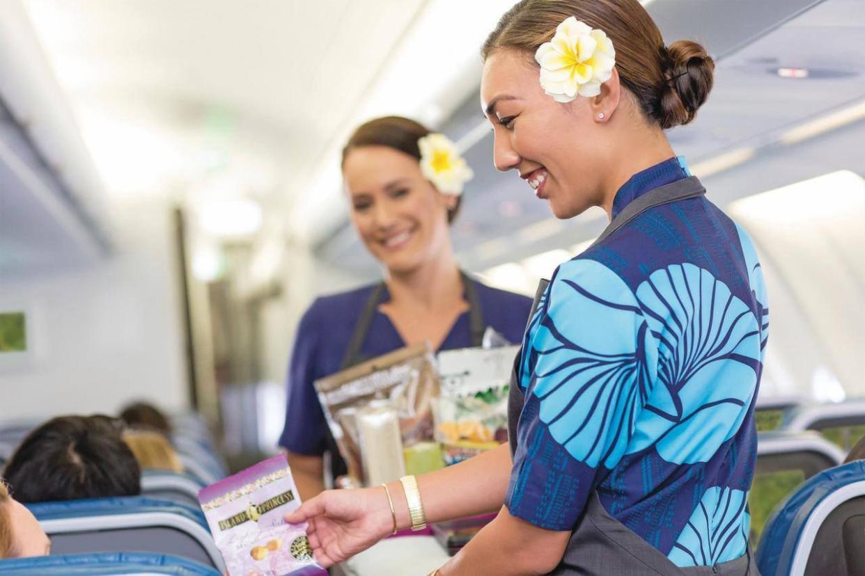 hawaiian airlines flight attendant offering snacks to passengers